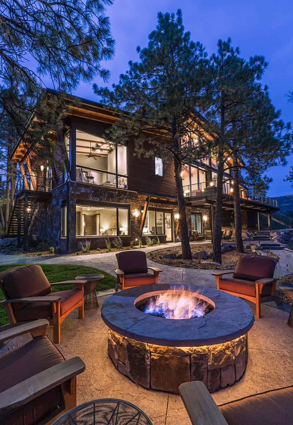 A fire pit in front of a modern mountain home
