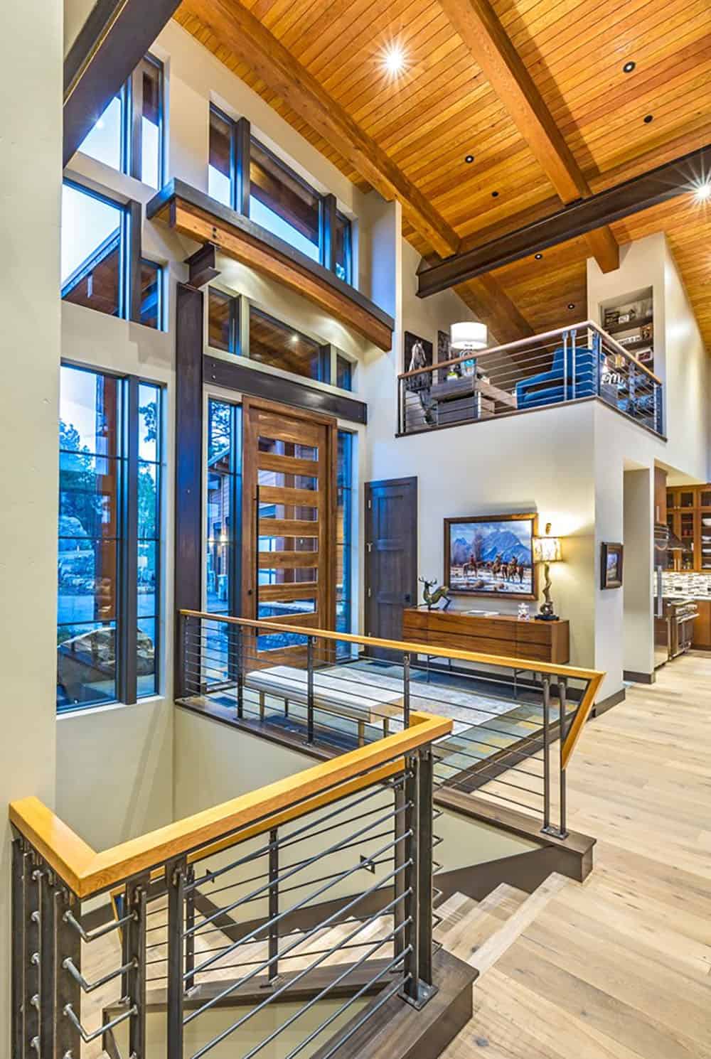 A large open concept living room with wood ceilings and a staircase