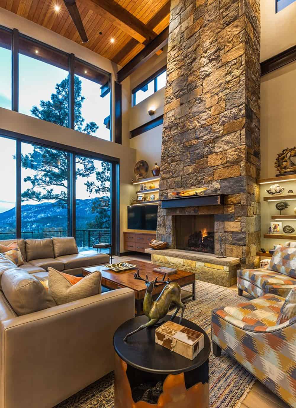 A large living room with stone fireplace and large windows