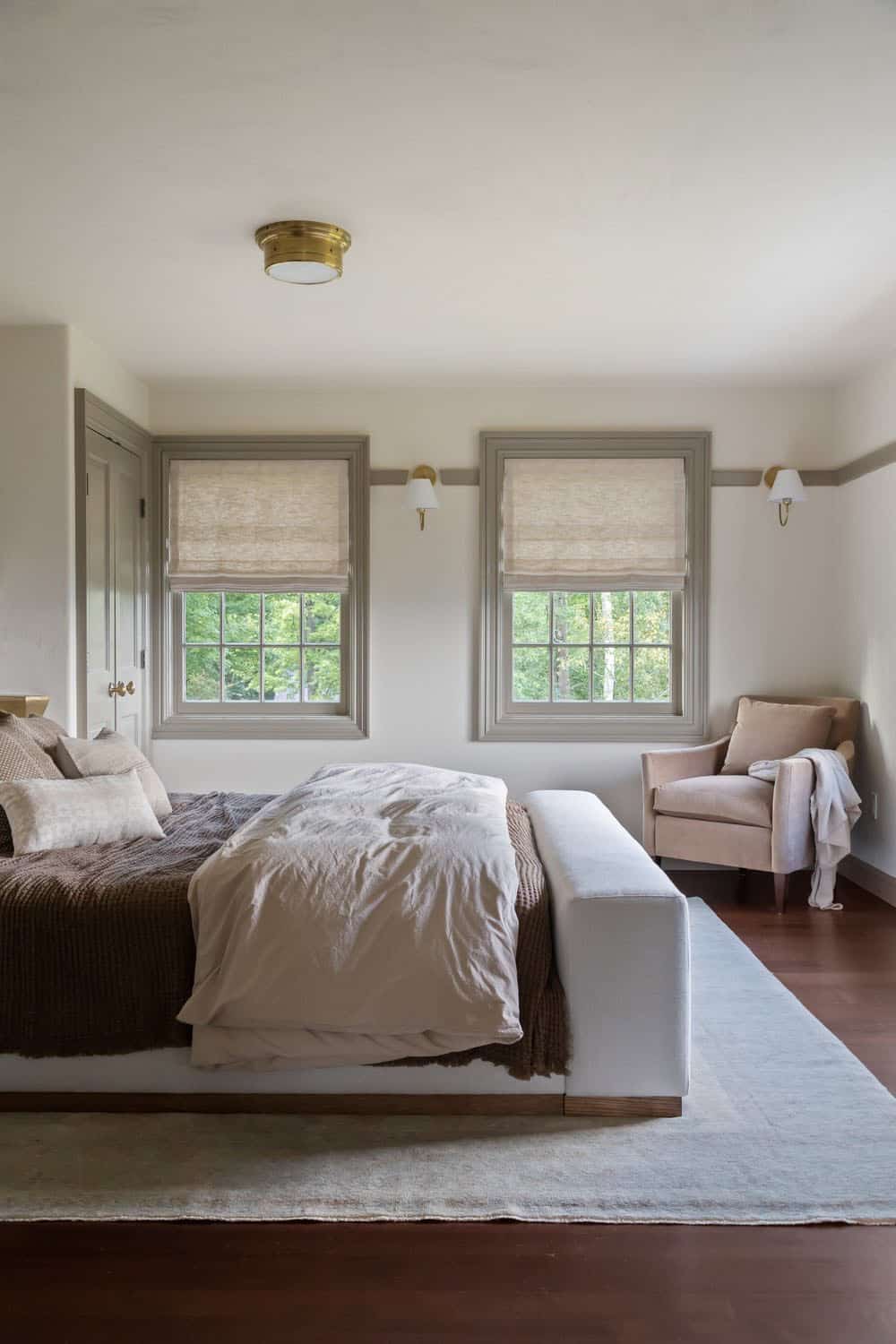 contemporary bedroom with a chair in the corner and two large windows