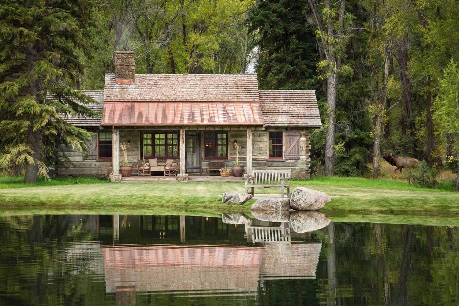 A rustic cabin with a porch and a pond view