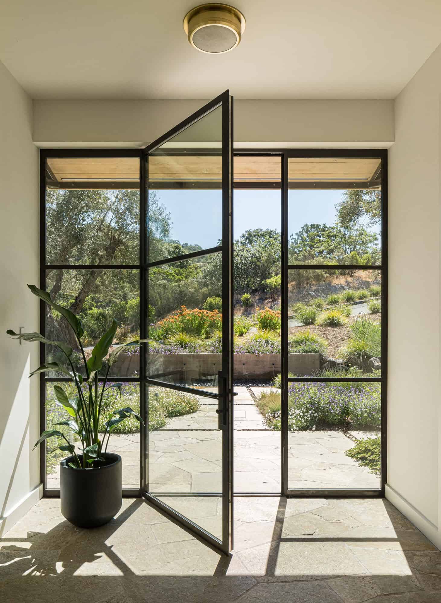 contemporary home entry with a glass and steel pivoting door