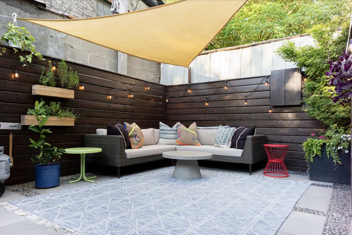 backyard patio design with a sunshade, string lights, sofa and round table