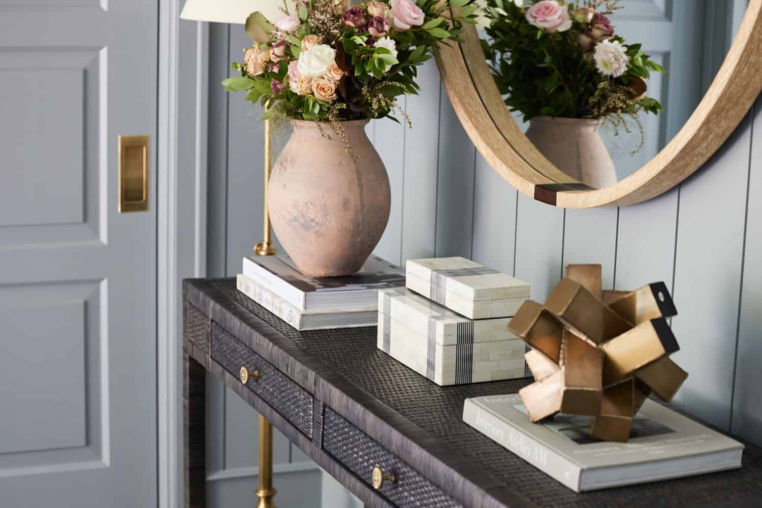A vase of flowers sits on a table next to a mirror.