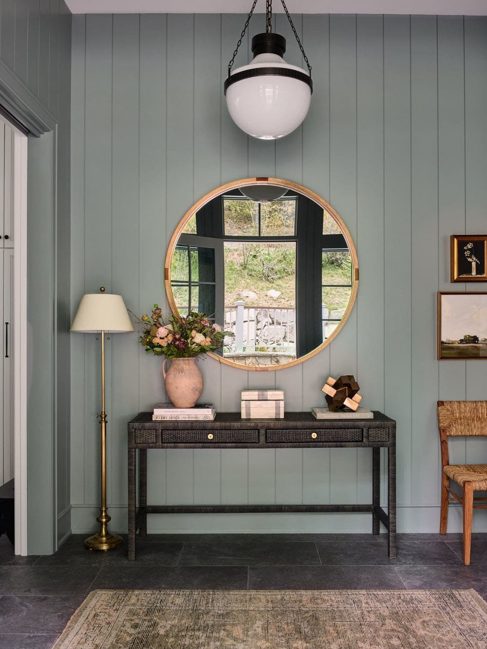 A foyer with a round mirror and a wooden table.