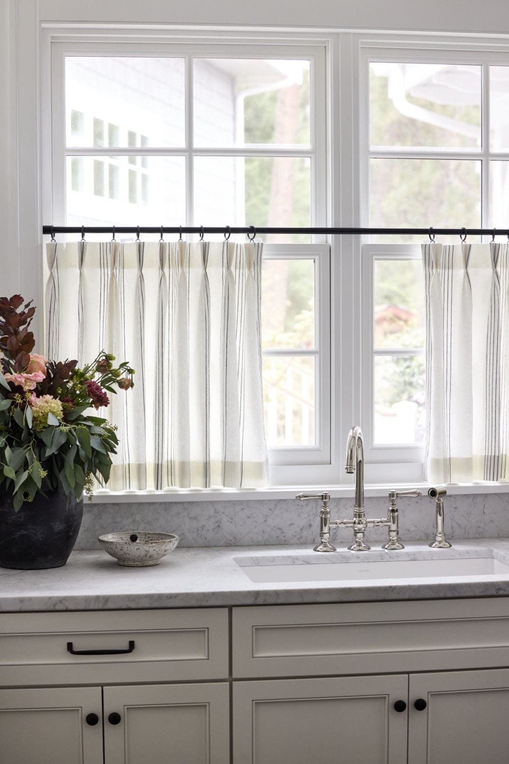 A laundry room window with curtains and a sink.
