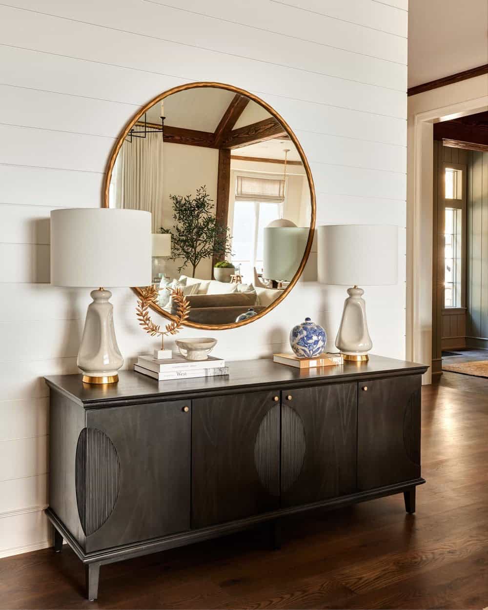 A black console table with two lamps and a mirror.