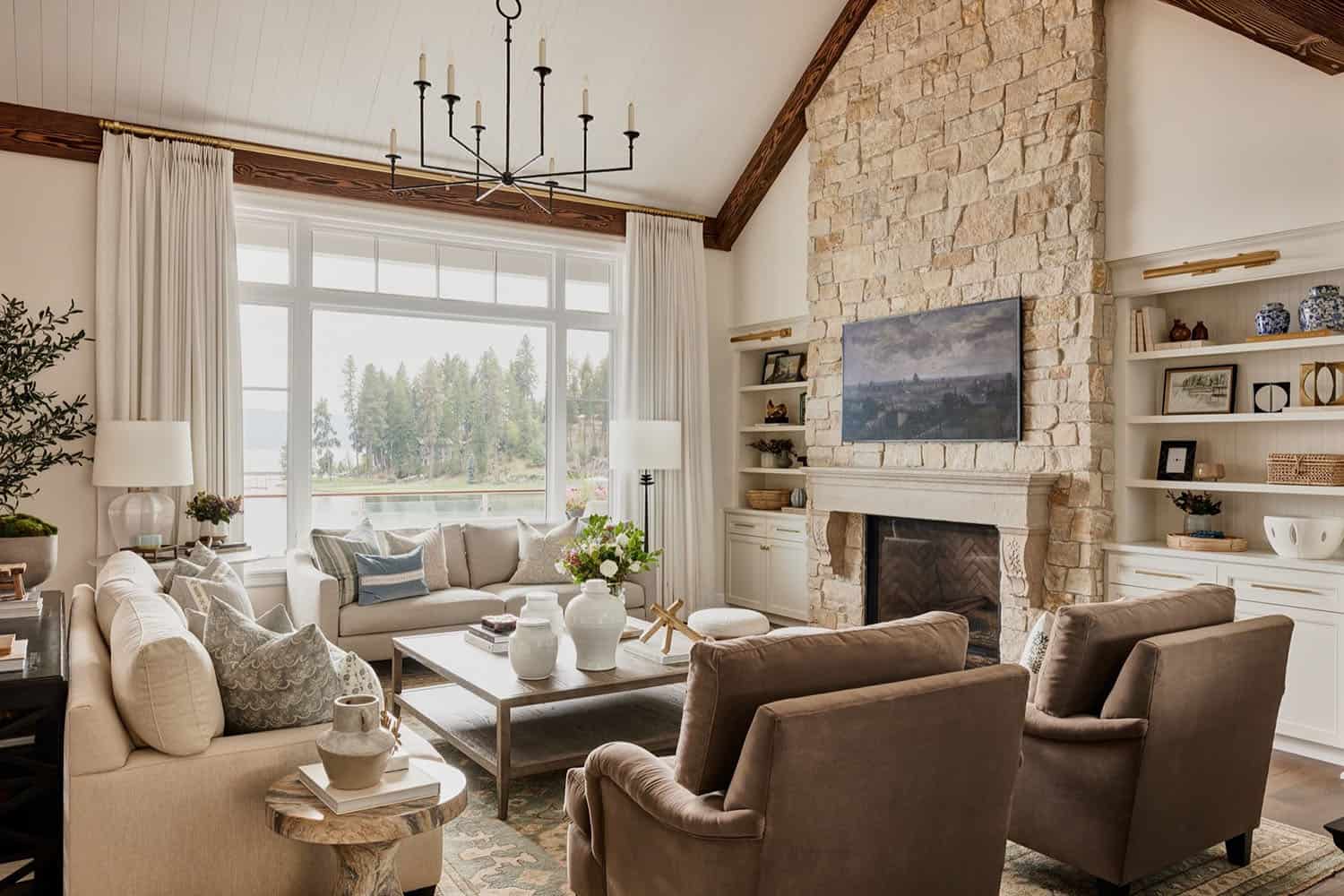 A living room with a stone fireplace and a large window.