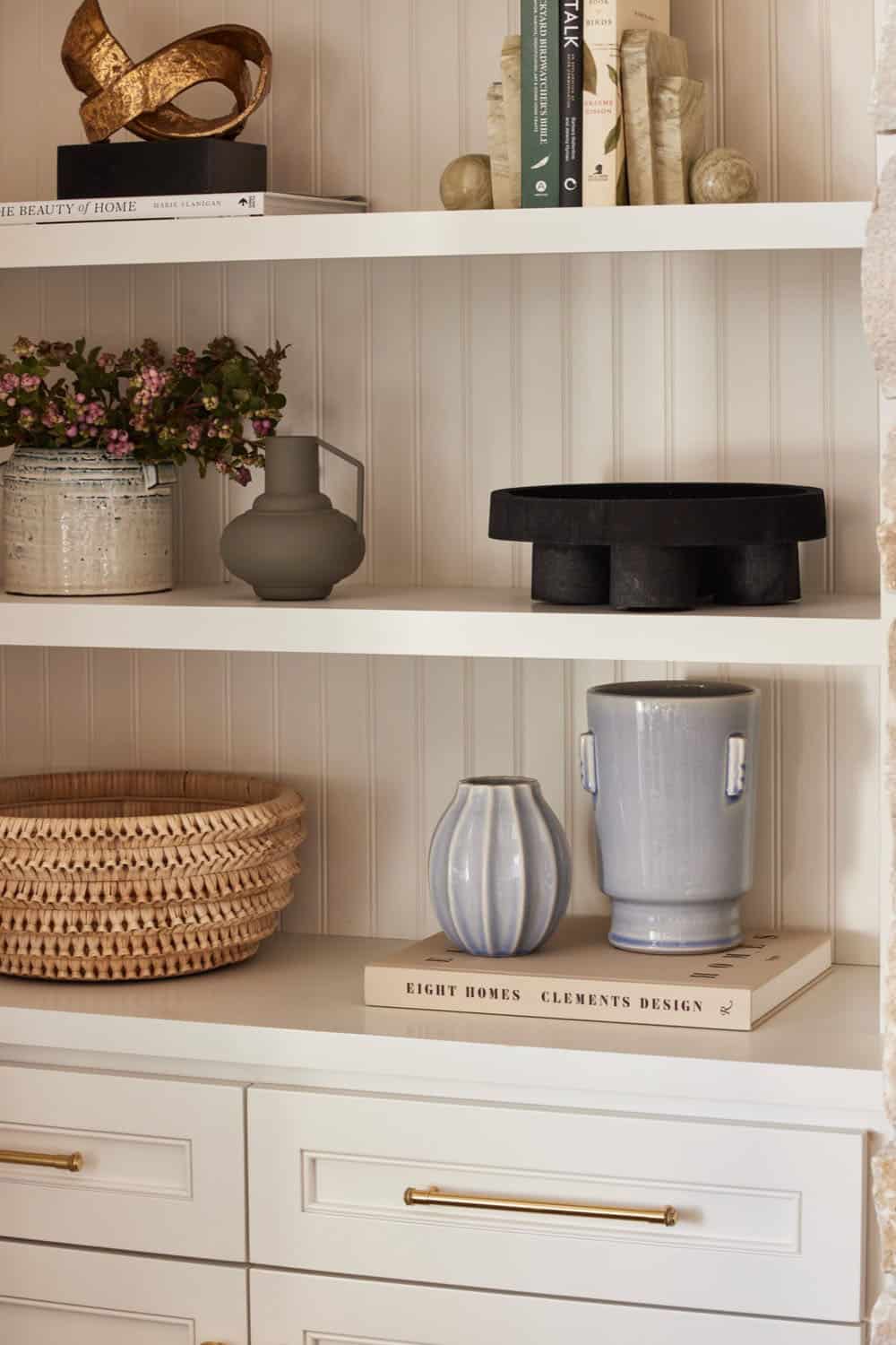 A white shelf with a vase and a basket.
