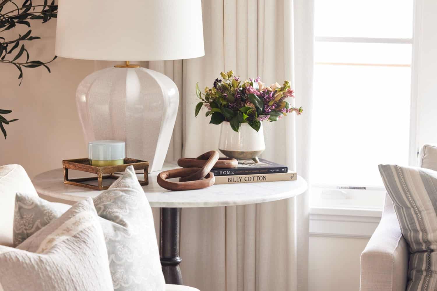 A white table with a lamp and a vase on it.