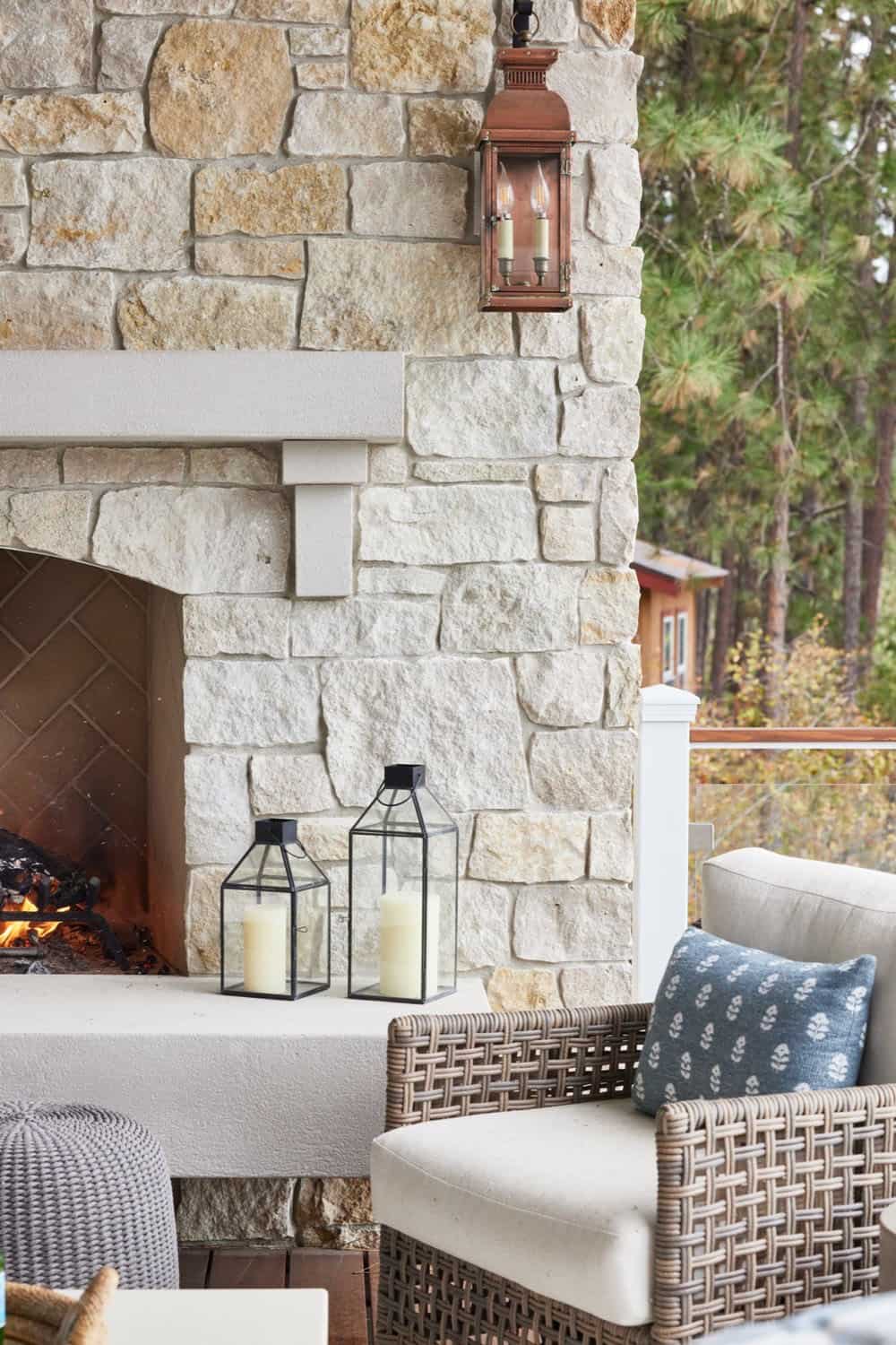 A stone fireplace with a wicker chair and a table.