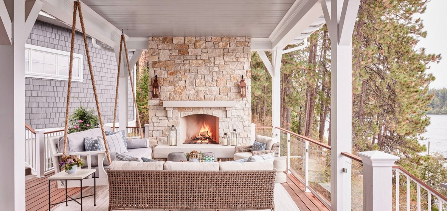 A porch with wicker furniture and a fireplace.