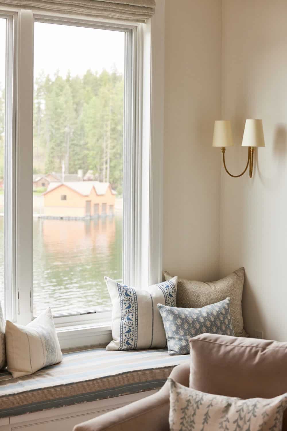 A window seat with pillows and a view of the lake.