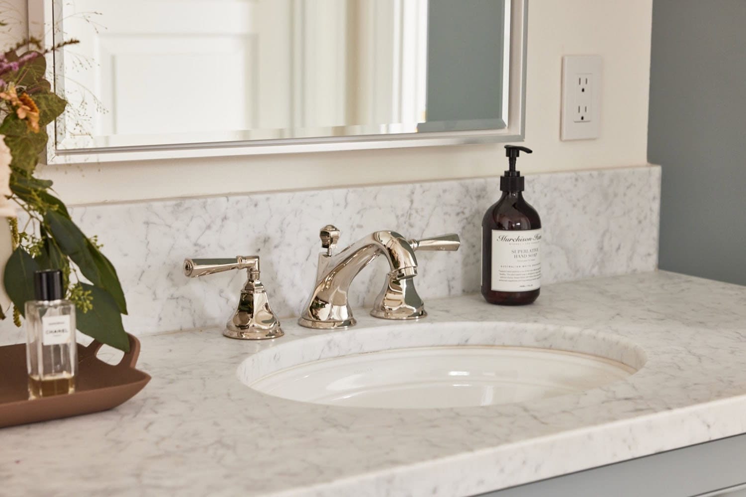 A bathroom sink with a mirror and flowers.