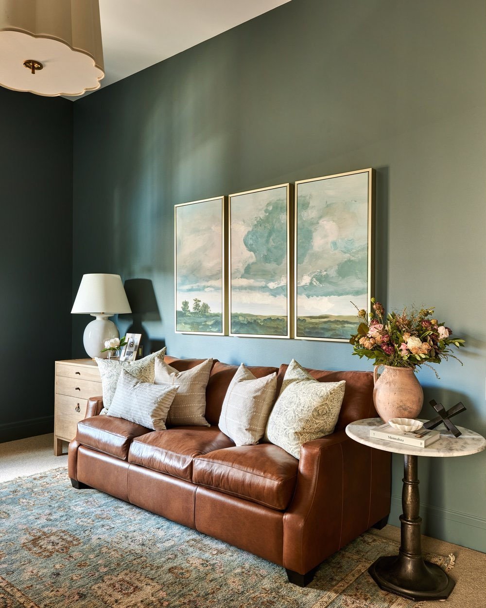 A home office with a leather sofa and paintings on the wall