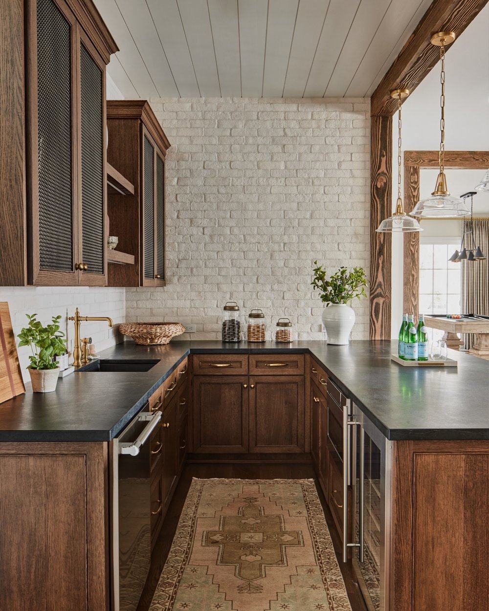 A home bar with wood cabinets and a rug.
