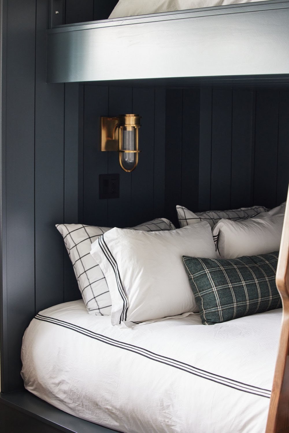 A bunk bed with a wooden headboard and a lamp.