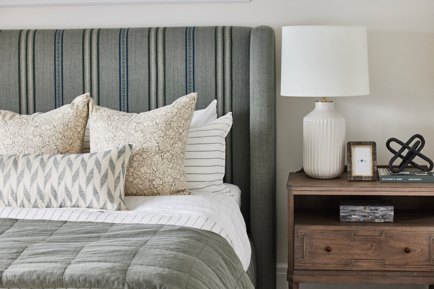 a bed with a striped headboard and a table lamp