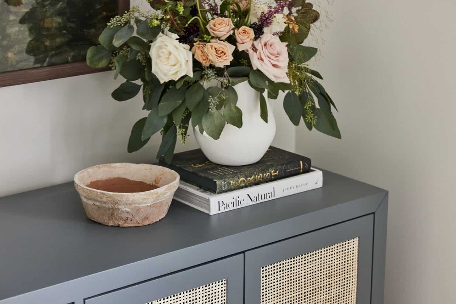 A vase of flowers sits on top of a gray sideboard.