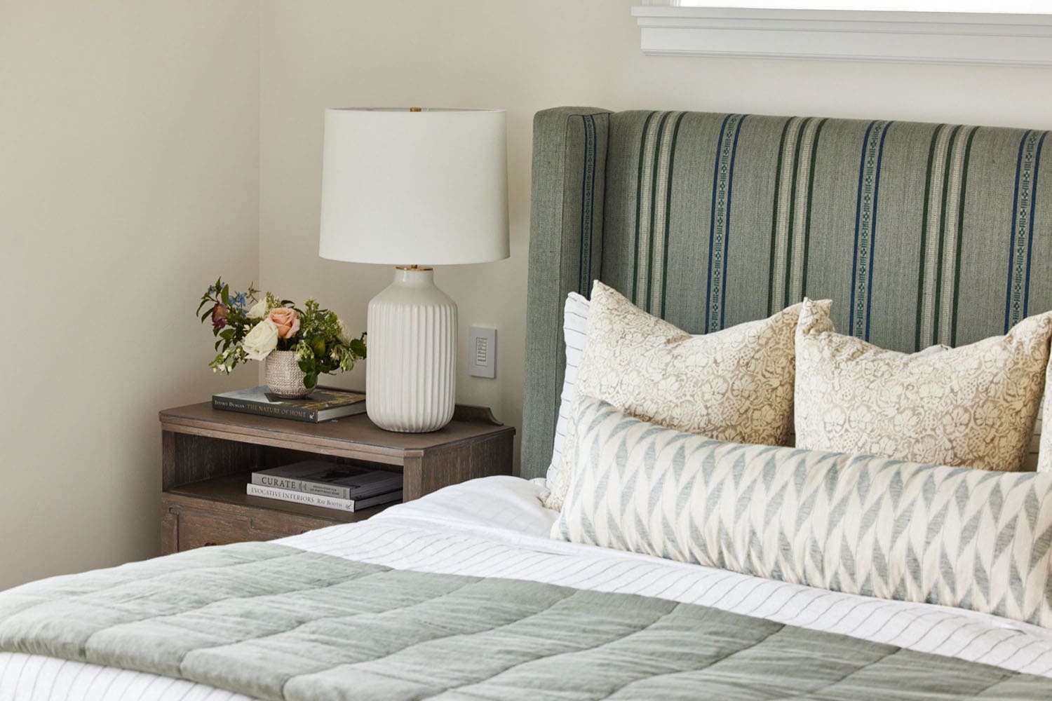 a bed with a striped headboard and a table lamp