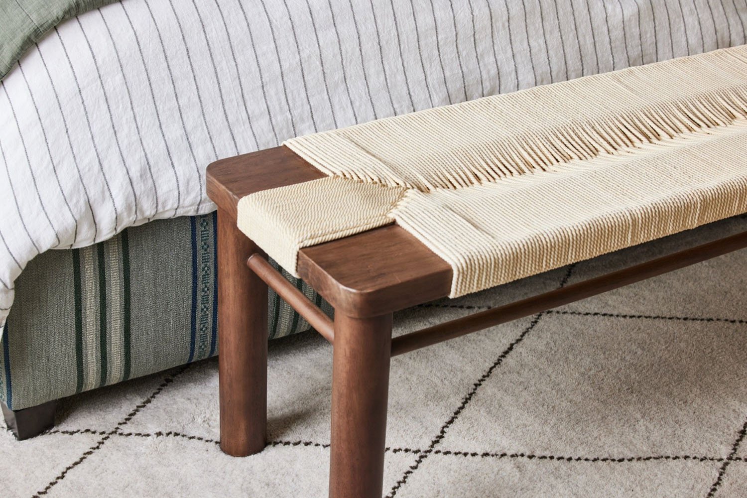 A bench with a woven seat and a bed.