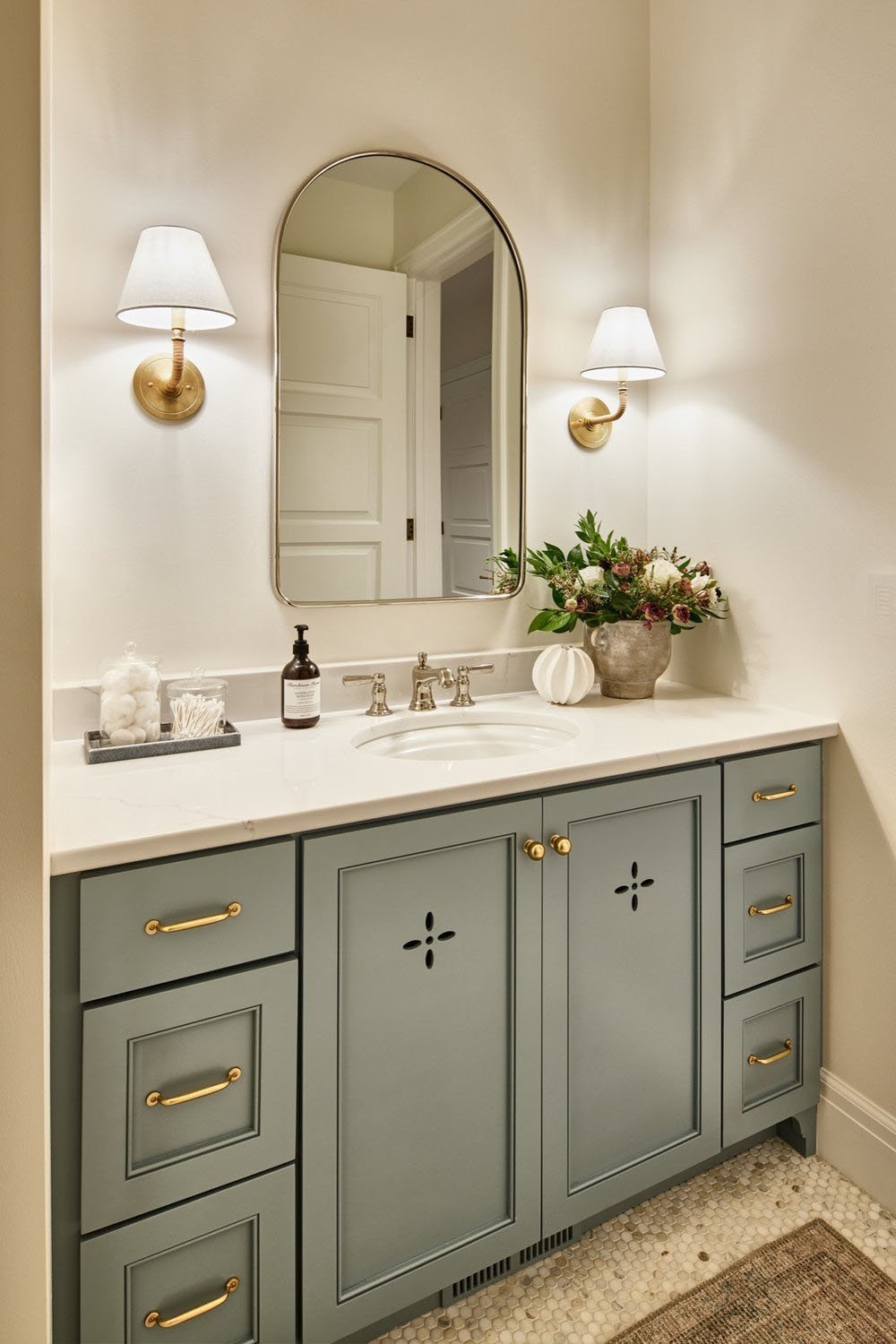 A bathroom with a blue vanity and gold fixtures.