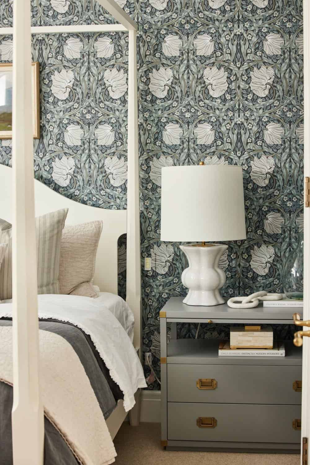 A bedroom with a four poster bed and a lamp.