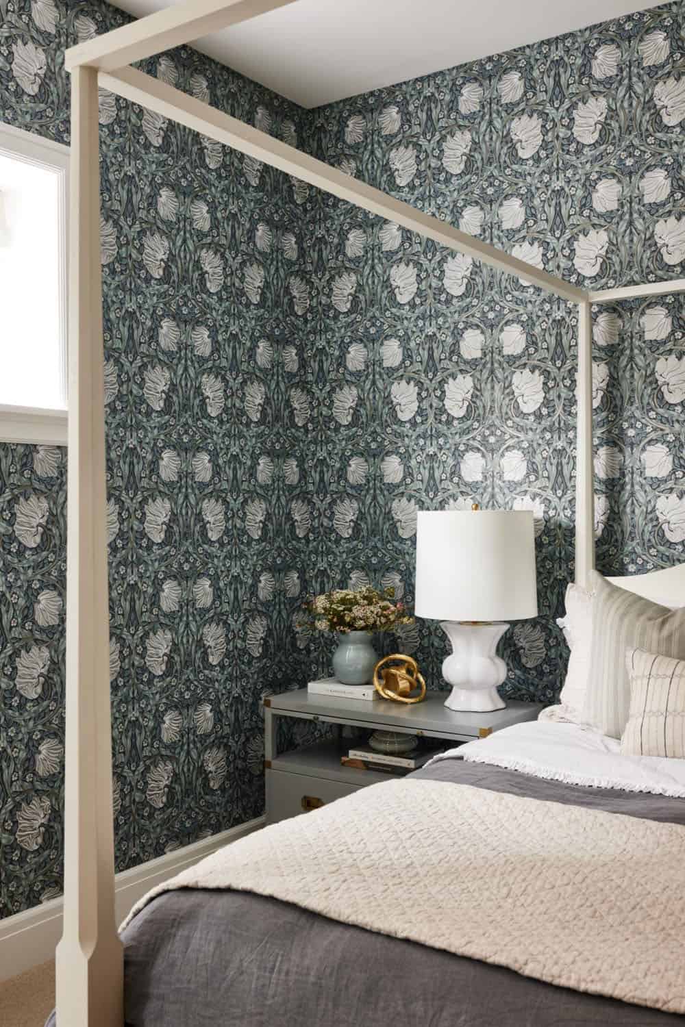 A bedroom with a four poster bed and wallpaper.