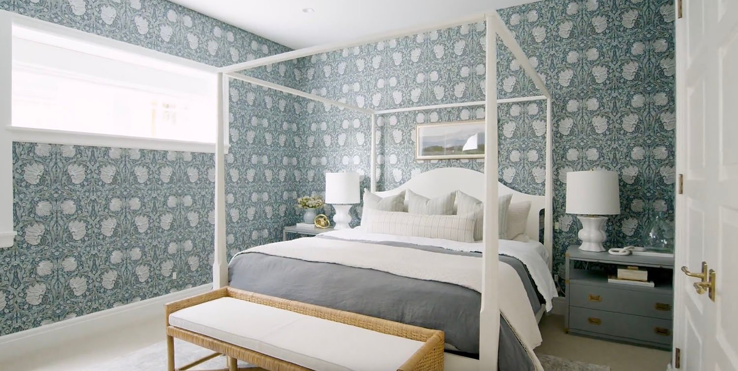 A bedroom with a white canopy bed and blue wallpaper.
