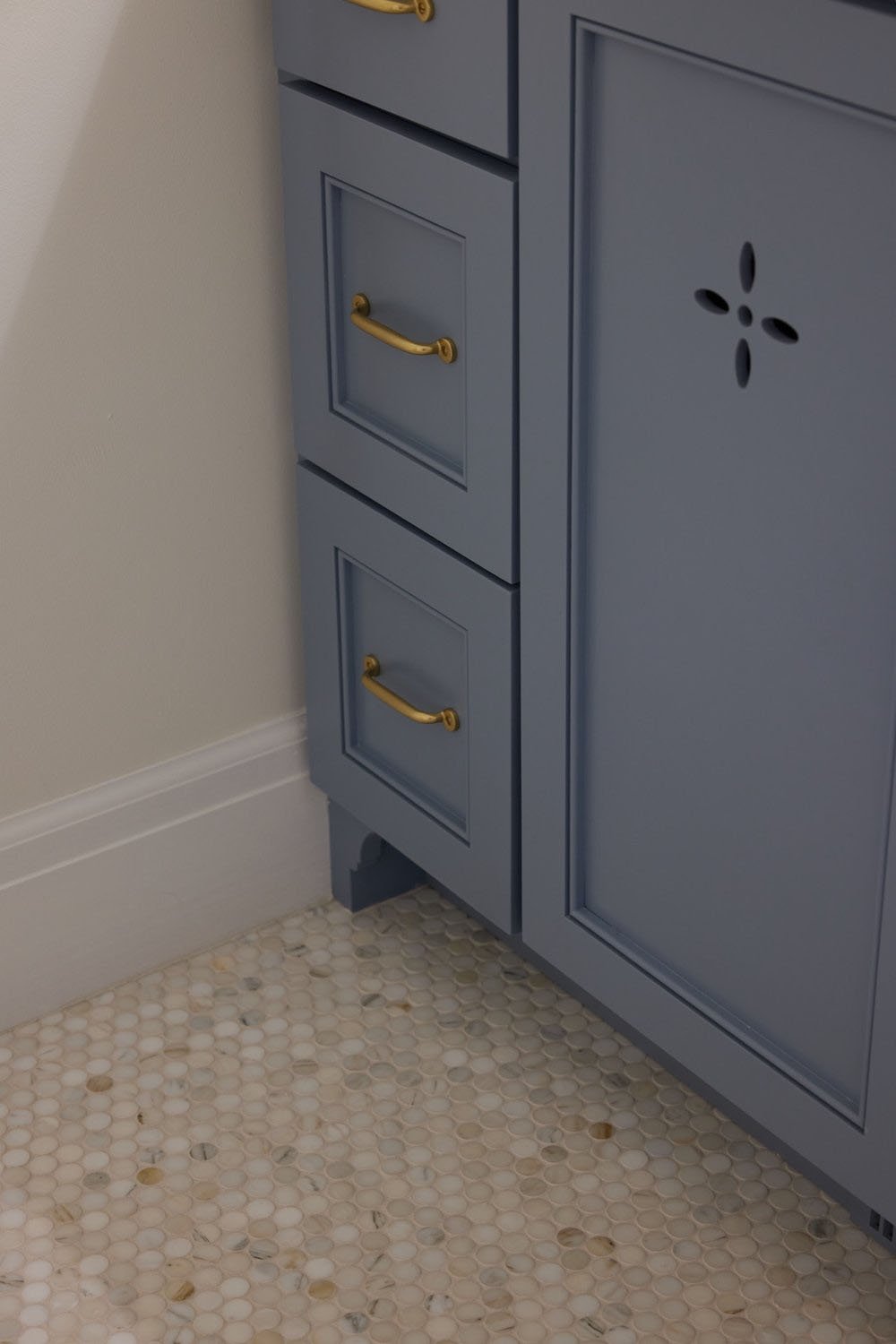 A bathroom with a blue vanity and gold knobs.