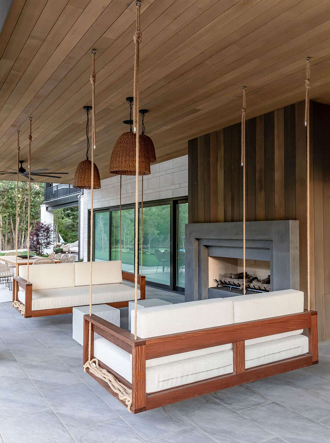 contemporary covered patio with hanging daybeds and a fireplace