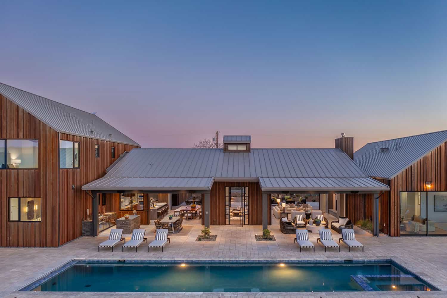 contemporary vineyard home exterior with a pool at dusk