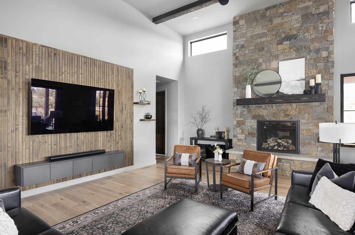 A living room with a stone wall and a flat screen tv.