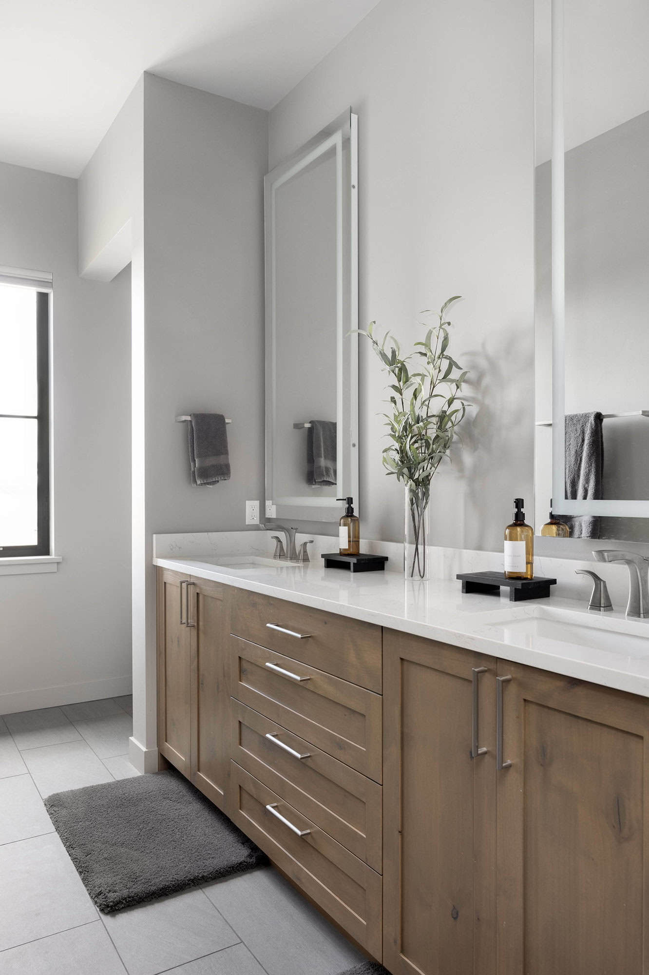 A modern bathroom with a large mirror and wooden cabinets.