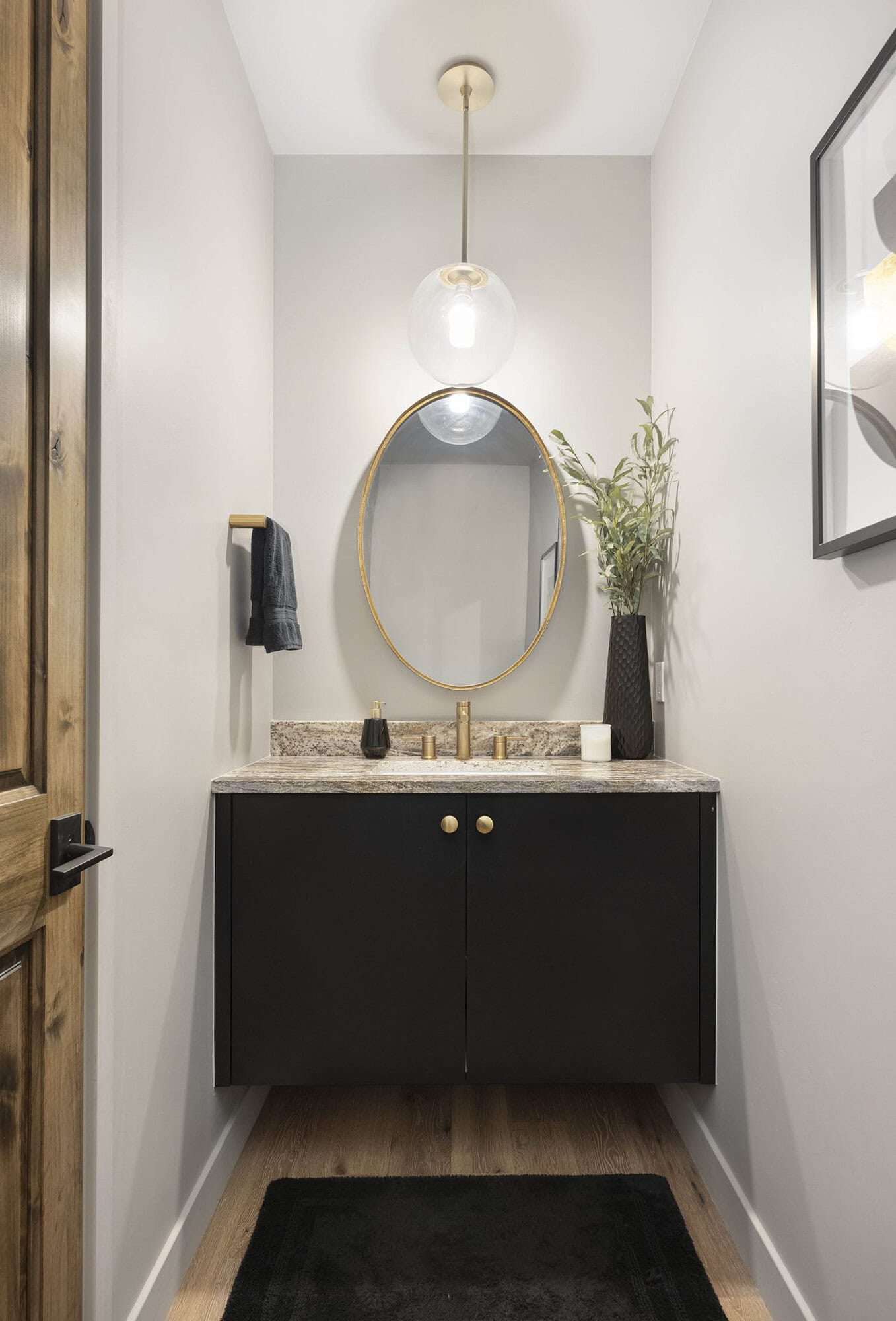 powder bathroom with a black vanity and gold mirror.