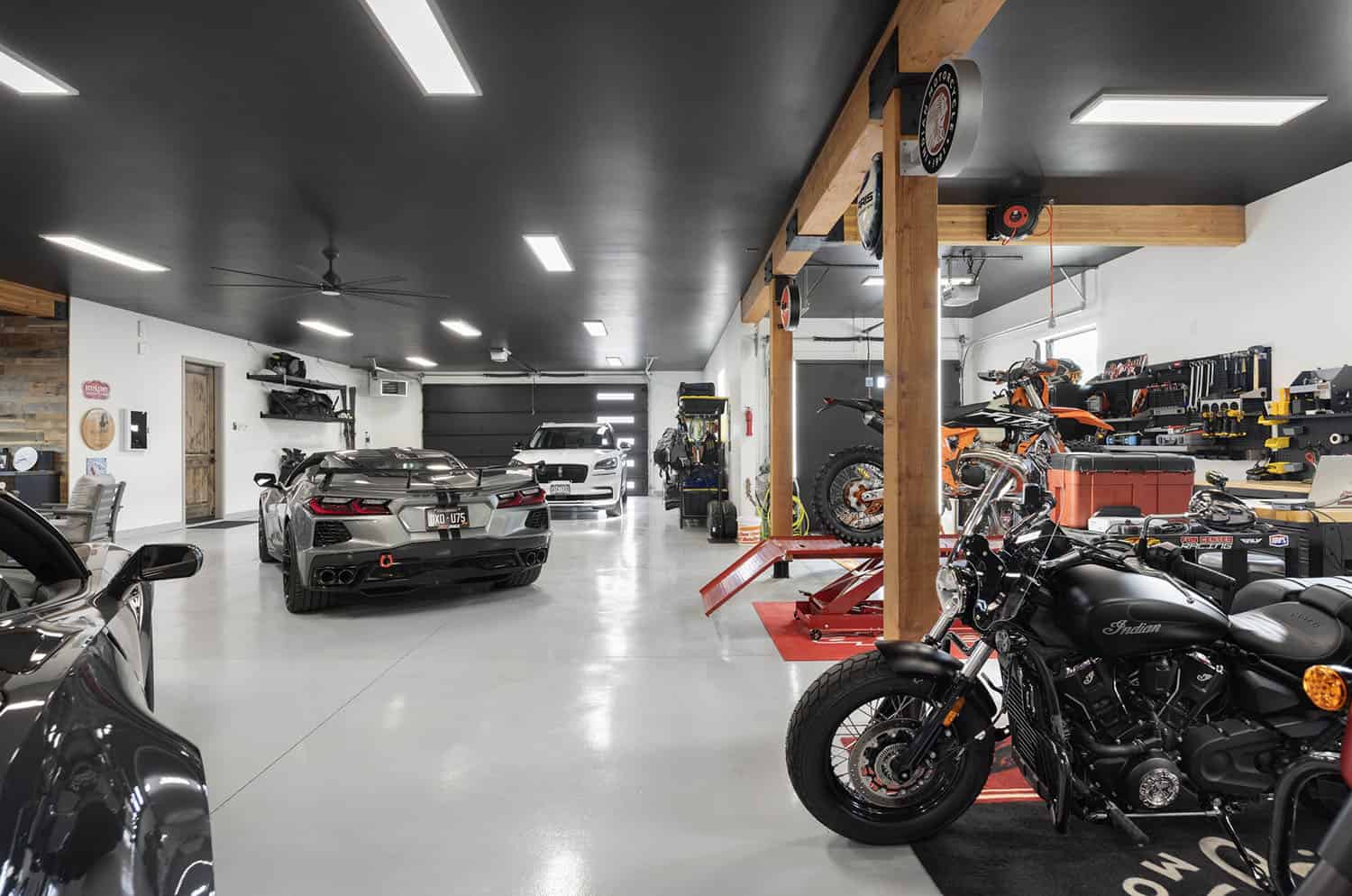A garage with motorcycles and cars in it.