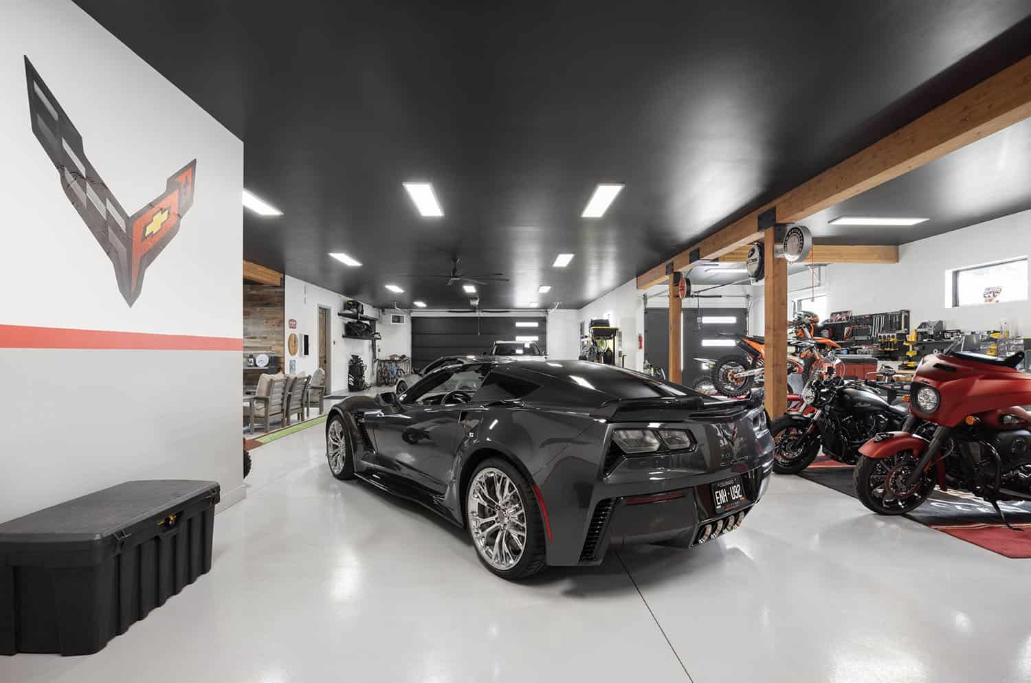 A garage with a black car and motorcycles.