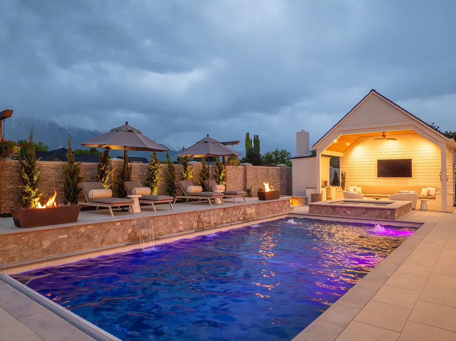 european style home exterior with a pool at dusk