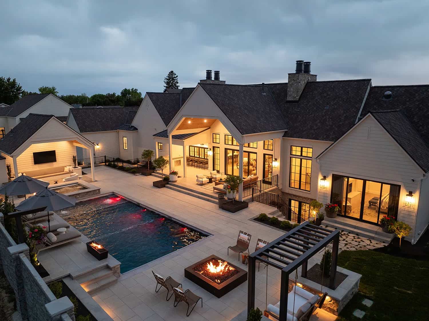 european style home exterior with a pool at dusk