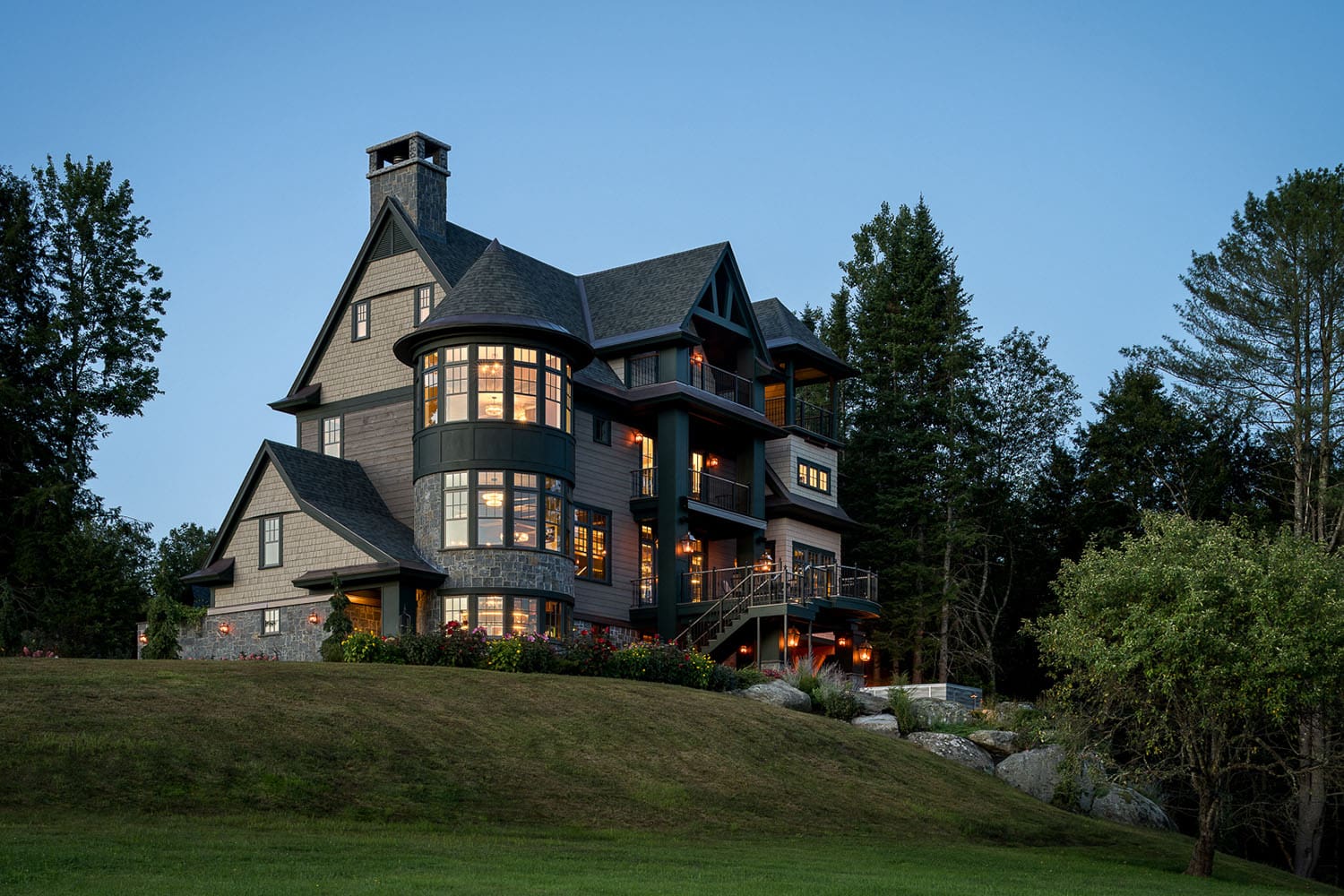 A large house with a large deck on top of a hill