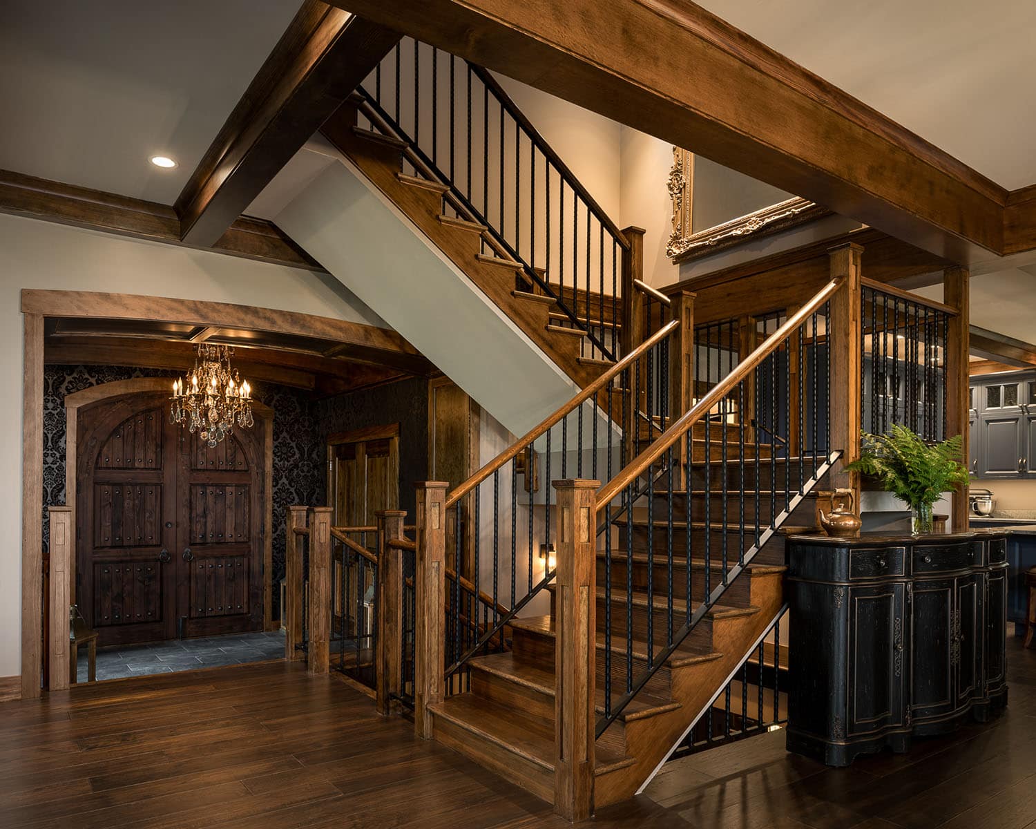 A staircase with wood stairs and a view of the kitchen in the background