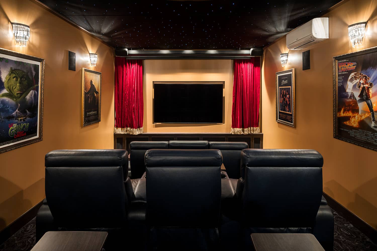 A home theater room with black leather seats and red curtains