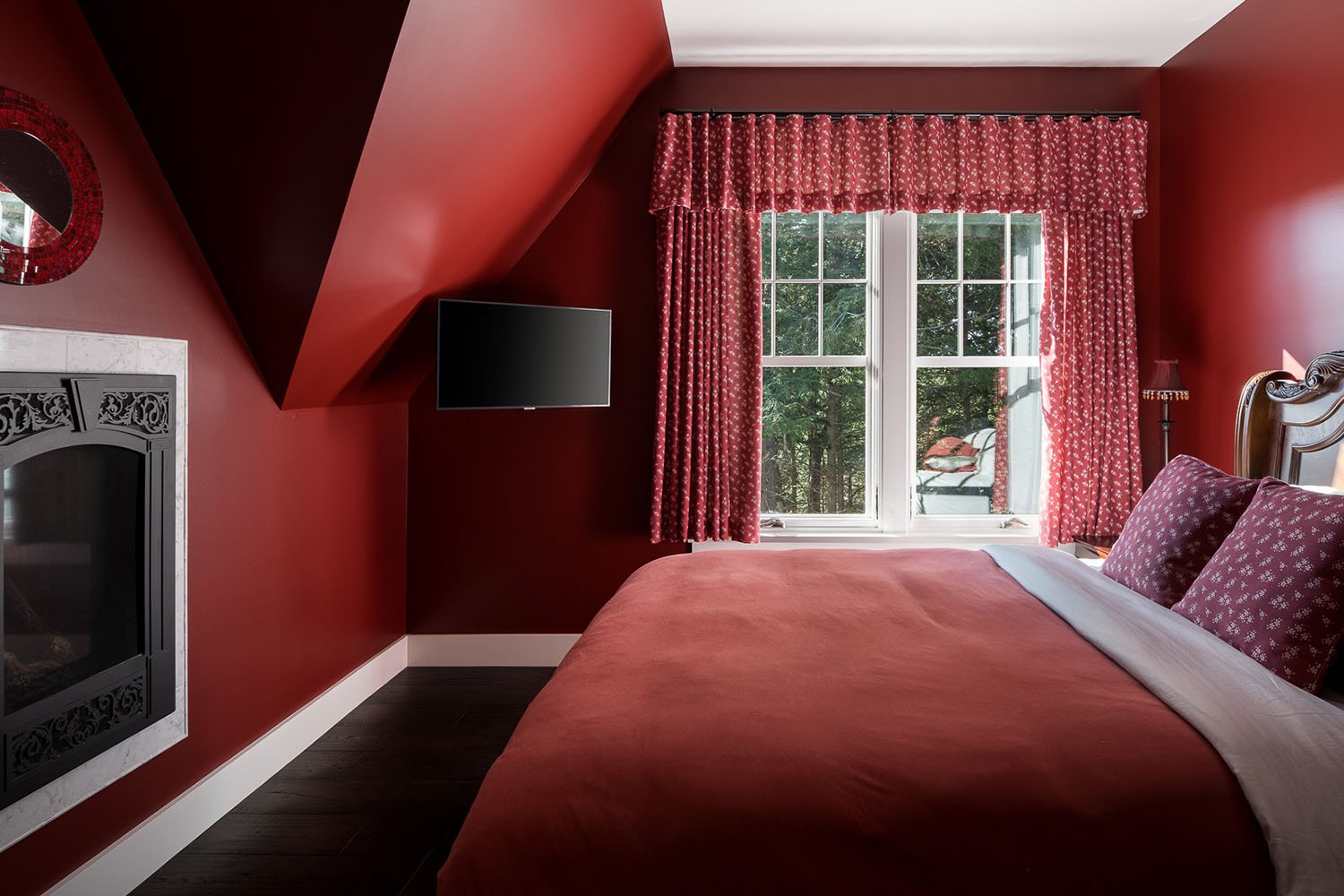 A bed with a red comforter, red walls and curtains