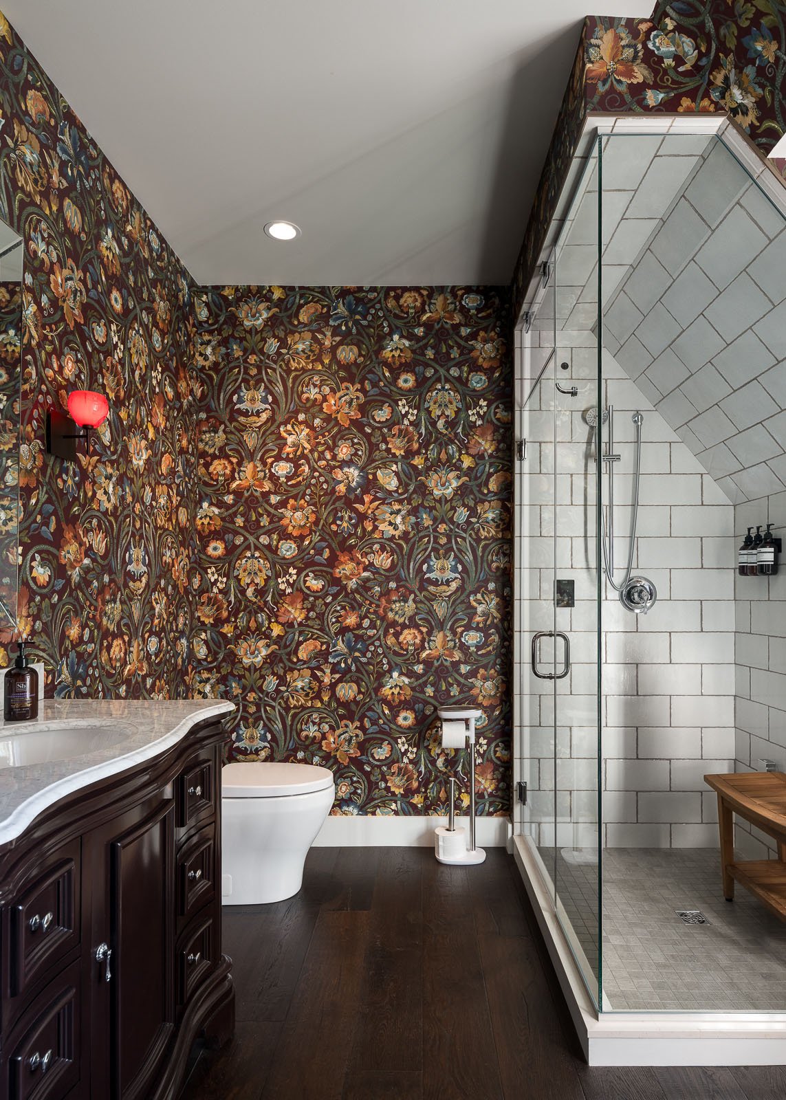 A bathroom with a shower and a toilet and wallpaper
