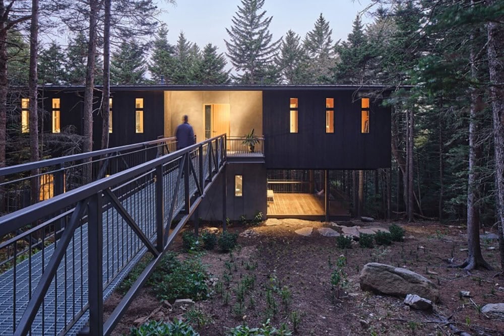 modern mountain cabin exterior with a bridge at dusk