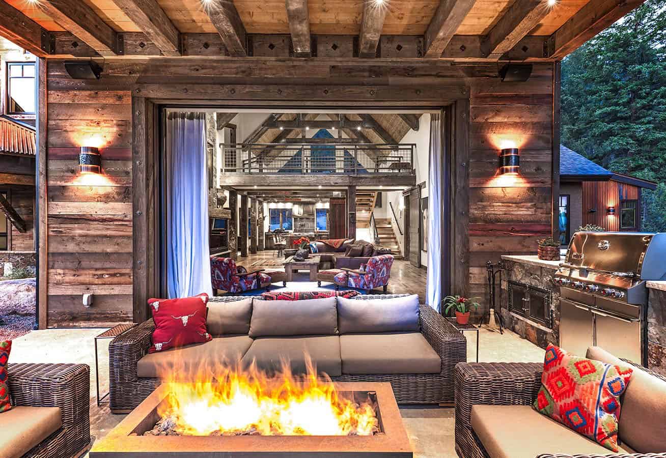 rustic western mountain home exterior patio with a fire pit at dusk