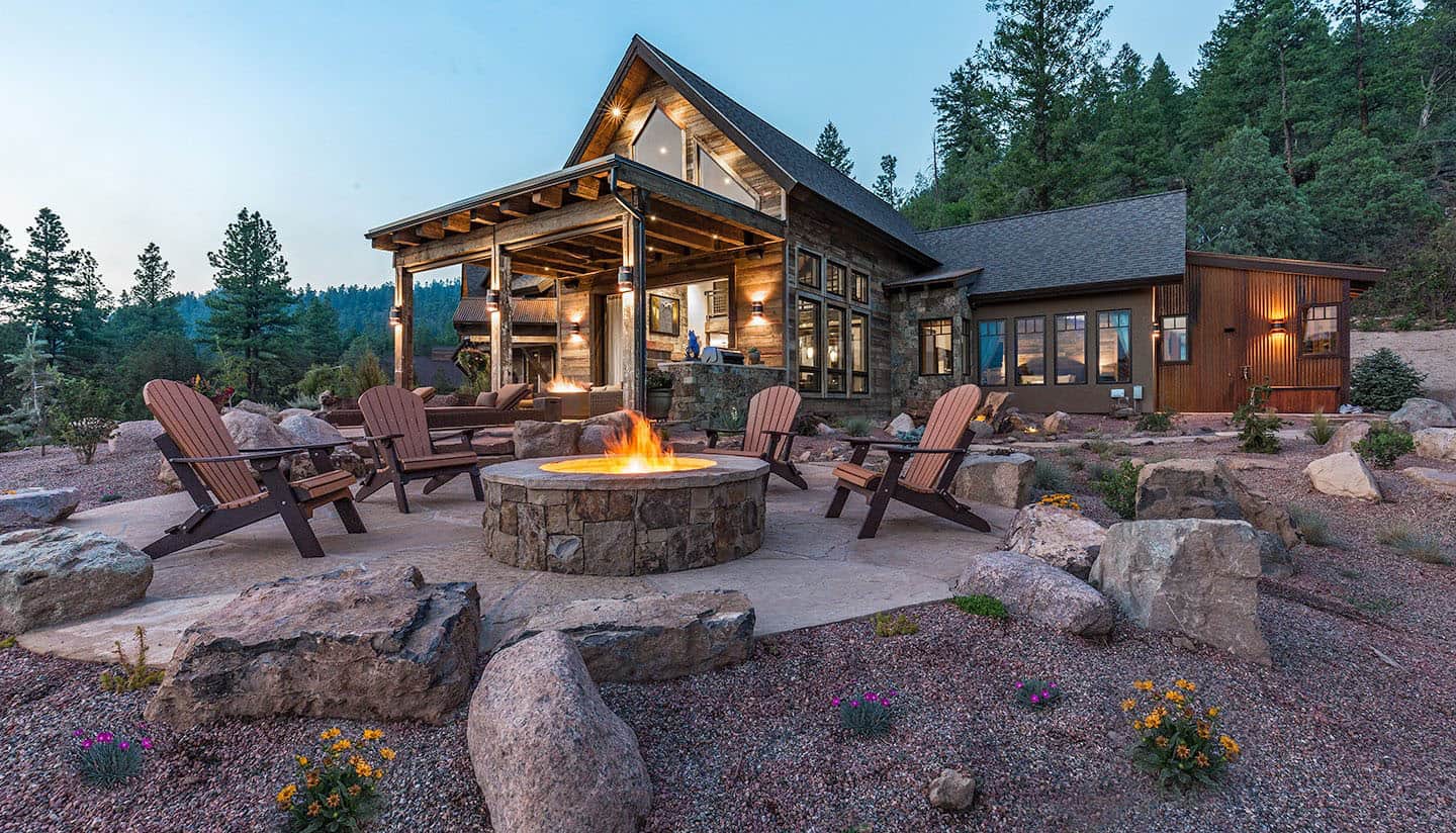 rustic western mountain home exterior patio with a fire pit at dusk