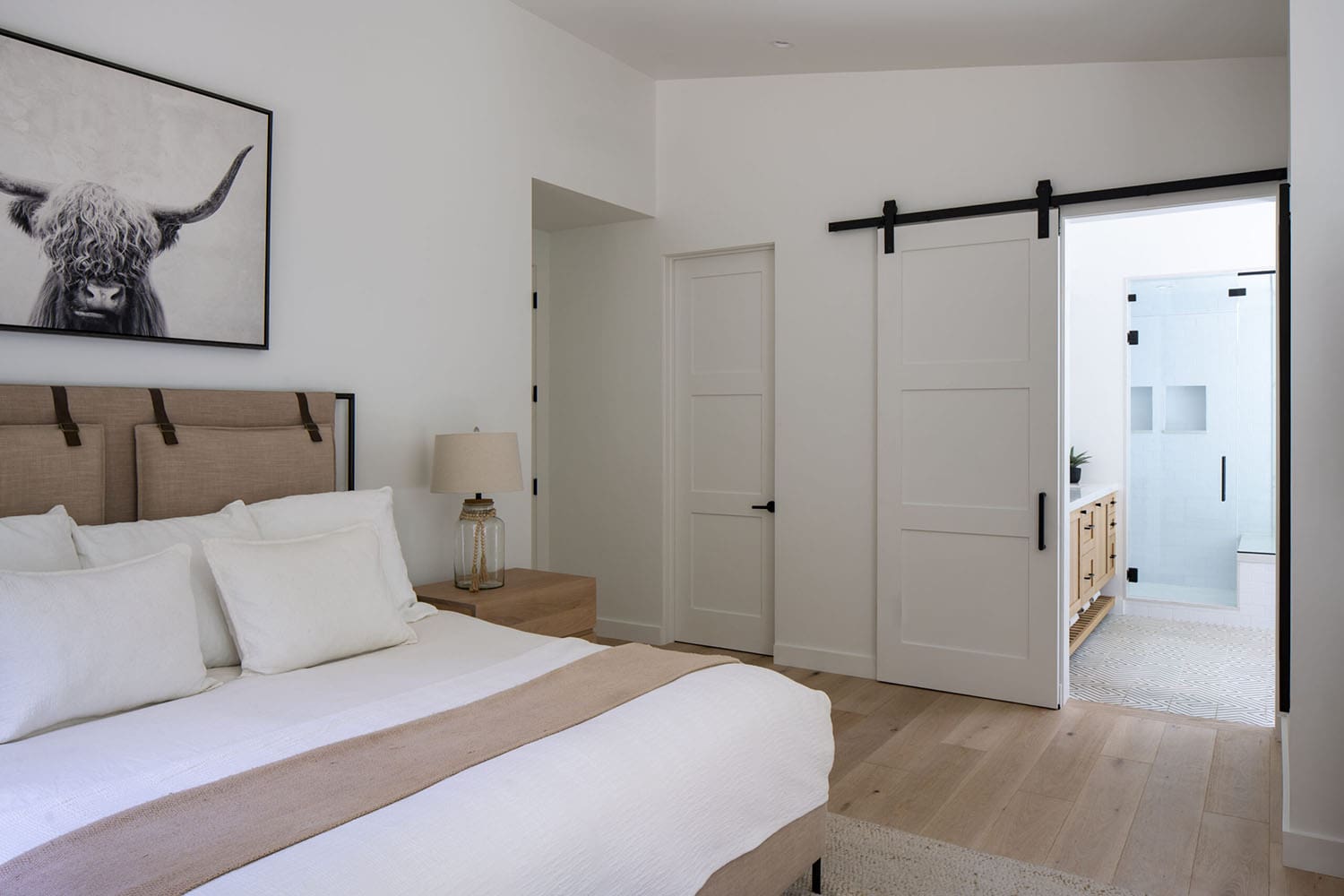 modern bedroom with a sliding barn door leading into the bathroom