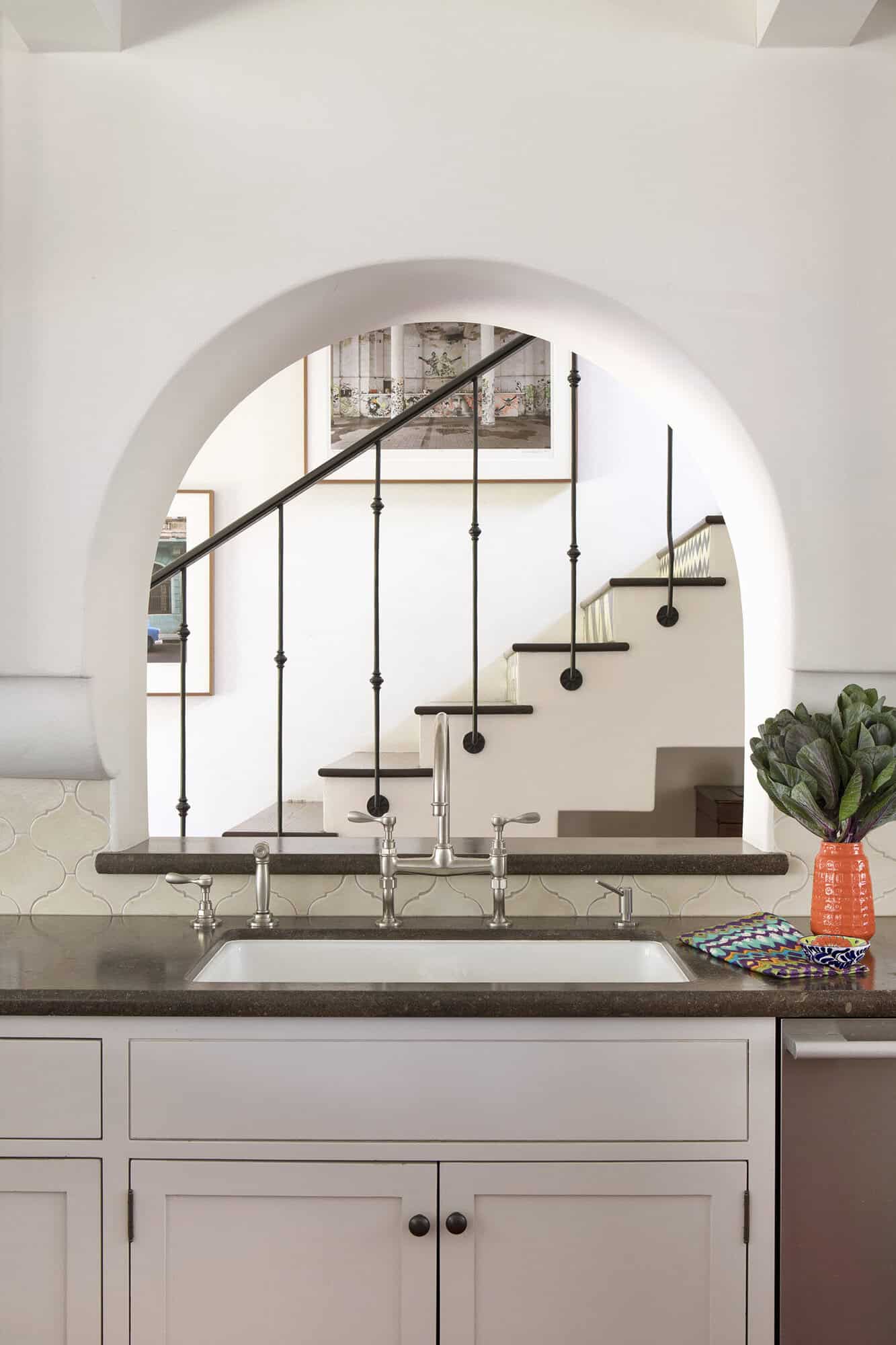 spanish colonial revival kitchen sink with an arch window framing the staircase