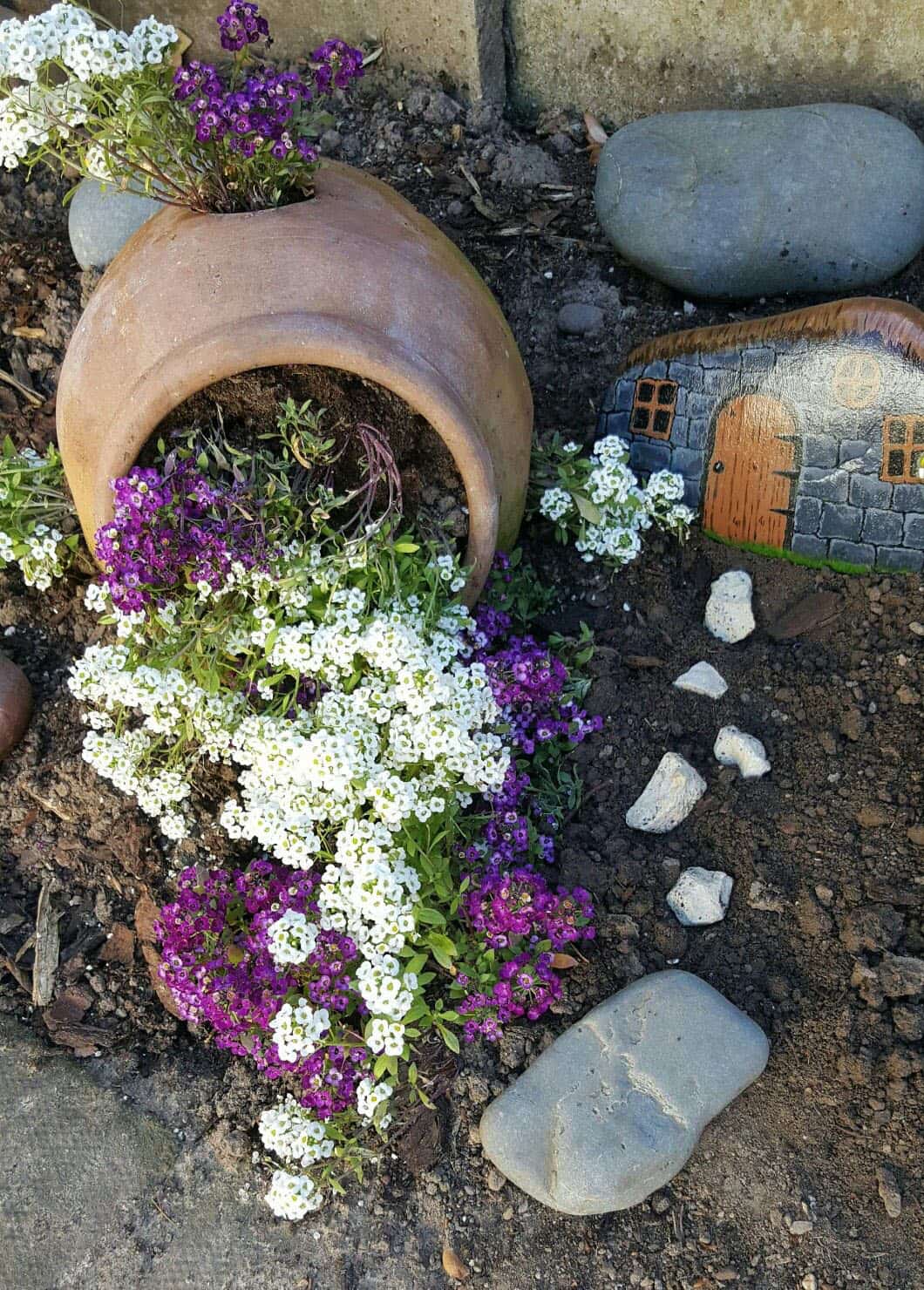 spilled flower pot next to a stone painting